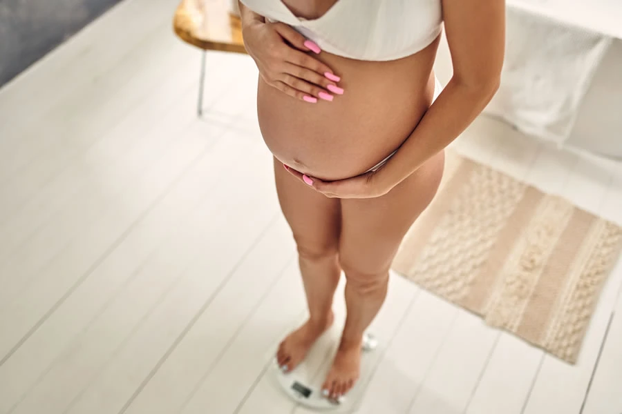 Trudna devojka u 26. nedelji trudnoce se meri na vagi.