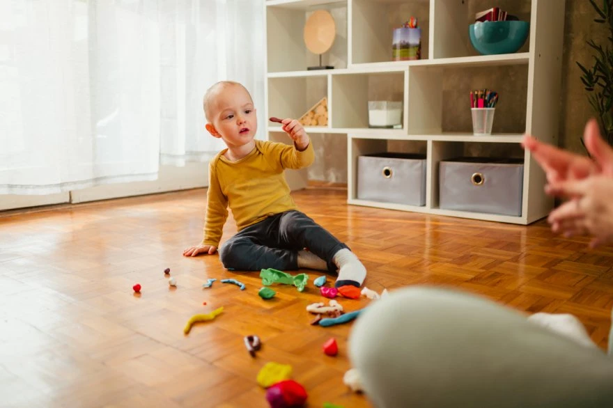 Dete se igra sa plastelinom u sobi